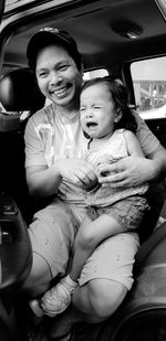 Full length of smiling woman sitting in car