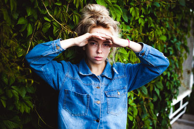 Portrait of young woman standing against plants