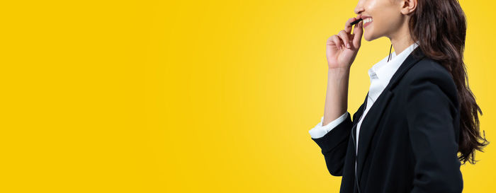 Side view of woman standing against yellow wall