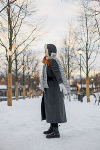 Rear view of woman standing on snow covered field