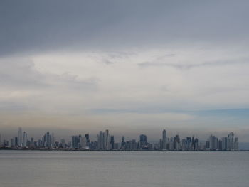 Sea and buildings in city against sky