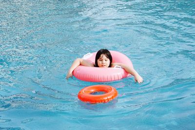 High angle view of girl with inflatable ring swimming in pool