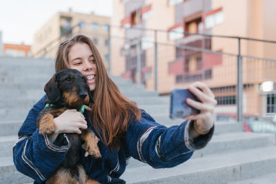 Alternative young adult woman making a selfie photo with her dog