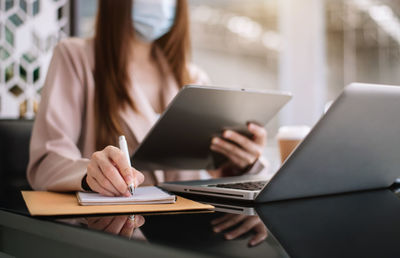 Midsection of woman using laptop on table