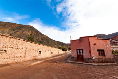 Road by buildings against blue sky