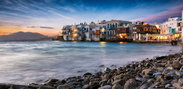 Buildings by sea against sky during sunset at mykonos