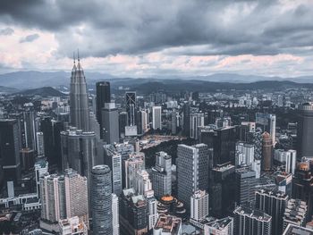 Aerial view of city buildings against cloudy sky