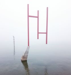 Wooden posts in lake against sky