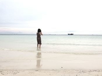 Rear view of person standing on beach against clear sky