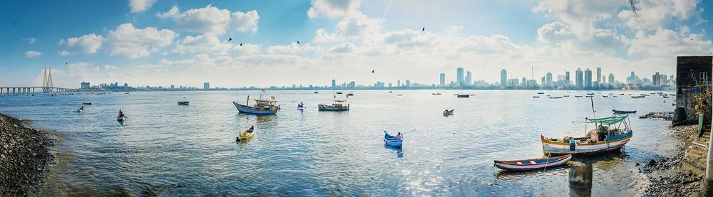 Panoramic view of boats on sea against cloudy sky during sunny day