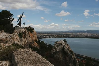 Scenic view of sea by mountain against sky