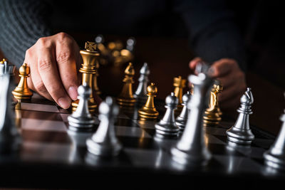 Cropped hands of person holding chess piece on board