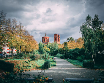 Road by trees against sky in city