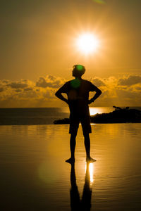 Silhouette man standing by sea against sky during sunset