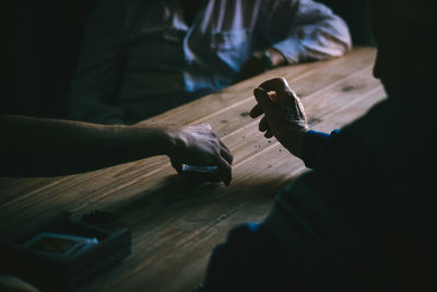 Male friends playing cards on wooden table