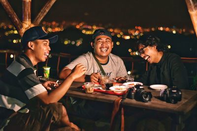 Happy friends sitting on table at cafe