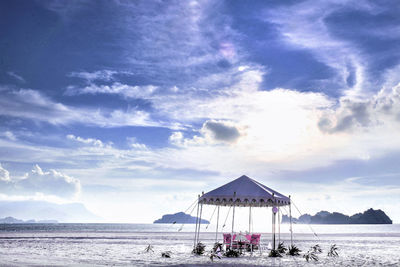 Beach tent on sand against cloudy sky