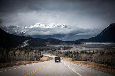 Cars on road by mountain against sky