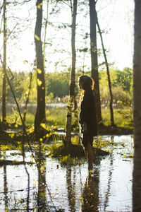 Side view of woman standing in lake at forest