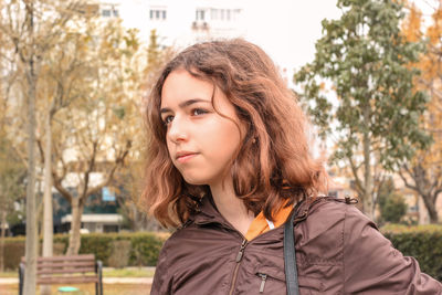 Beautiful young woman standing against tree