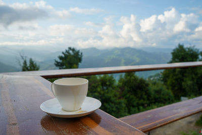 Coffee cup on table against sky