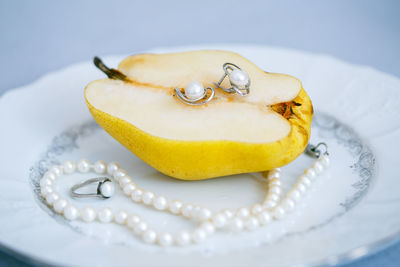 Close-up of jewelry and fruit in plate on table