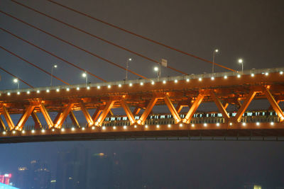 Illuminated bridge over river against sky at night