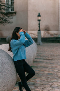 Side view of young woman standing against wall