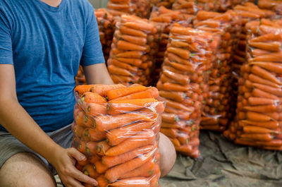 A farmer is packing freshly picked carrots into bags for sale. freshly harvested carrots. 