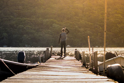 Rear view full length of man standing by river on pier