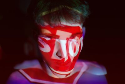 Close-up of shirtless man with light on face against black background