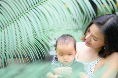 Mother holding son on street against plant