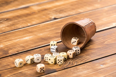 High angle view of dices spilling from container on wooden table