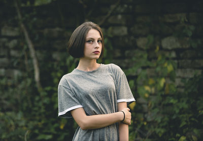 Portrait of young woman standing against wall