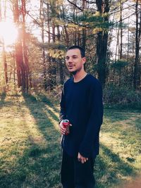 Young man standing on field in forest