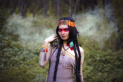 Young woman in traditional clothing carrying tortoise in forest