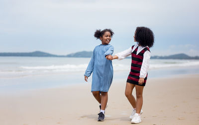 Friends enjoying at beach against sky