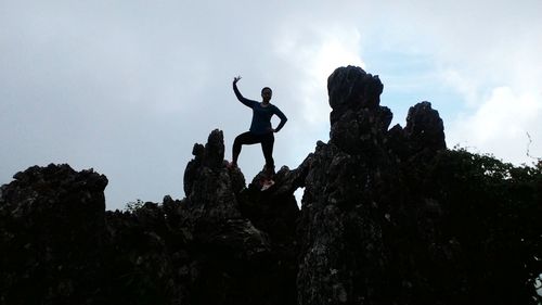 Low angle view of man on rock formation against sky