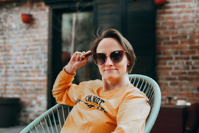 Beautiful young woman with short blond hair in casual clothing sitting and smiling.