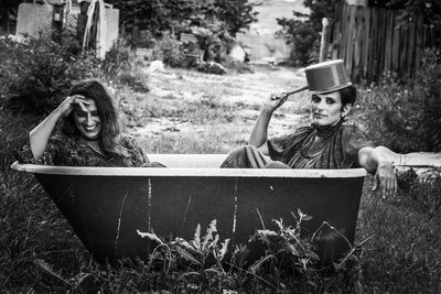 Portrait of woman sitting with sister in bathtub on field
