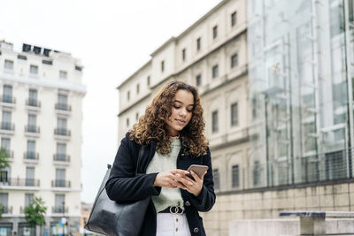 Full length of young woman using mobile phone