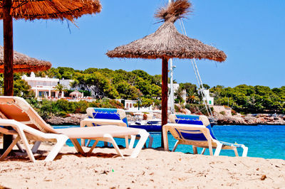 Chairs on beach against clear blue sky