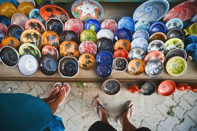 Low section of people standing by multi colored bowls