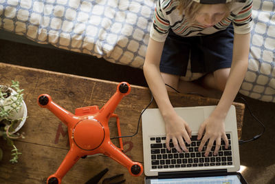 Overhead view of boy working on laptop computer by drone at home