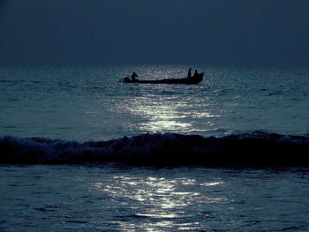 Silhouette people sailing on sea against sky