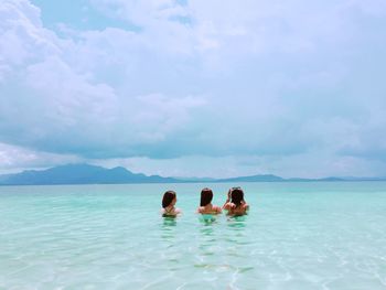 Rear view of women in swimming pool against sky