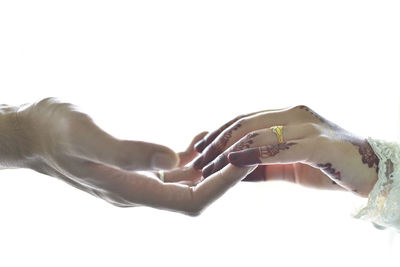 Cropped image of couple touching fingers over white background