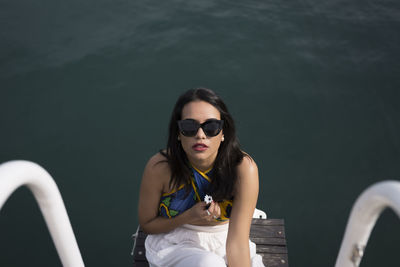 From above of a young woman in casual clothes and sunglasses looking at the camera