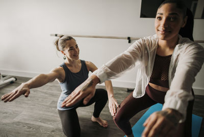 Female personal trainer coaches her female student how to squat