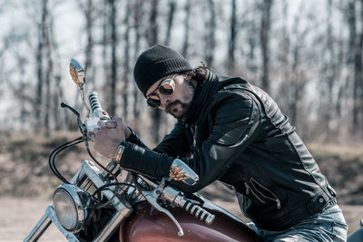 Mid adult man sitting on motorcycle in forest